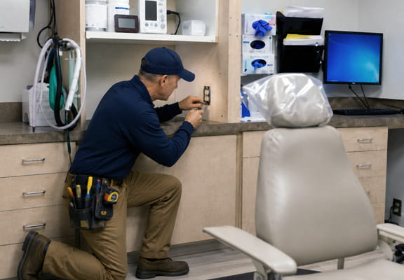 Electrician installing dedicated electrical outlet during dental office electrical buildout project