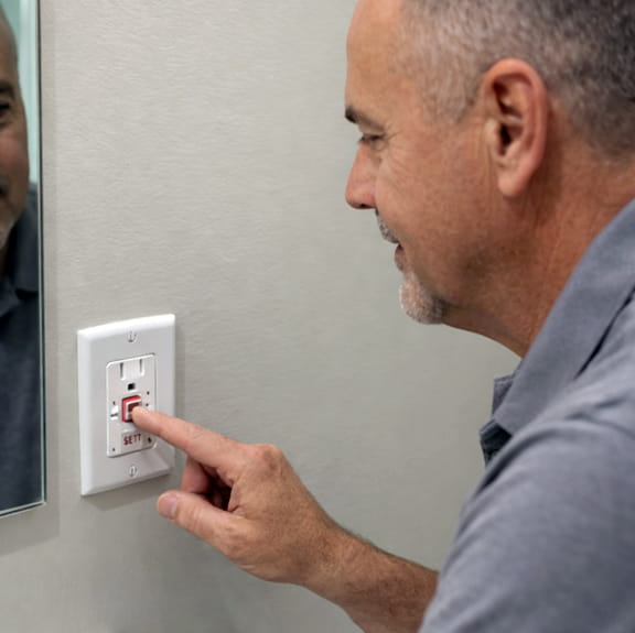 Homeowner resetting GFCI outlet to restore power to part of home