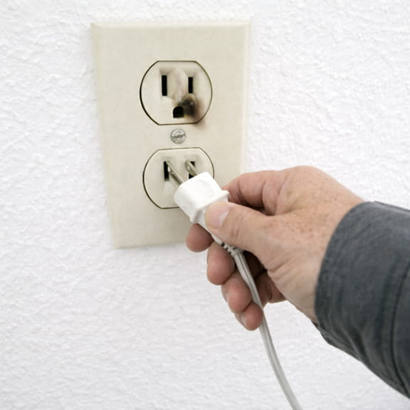 Scorched electrical outlet with plug being removed — electrical hazard