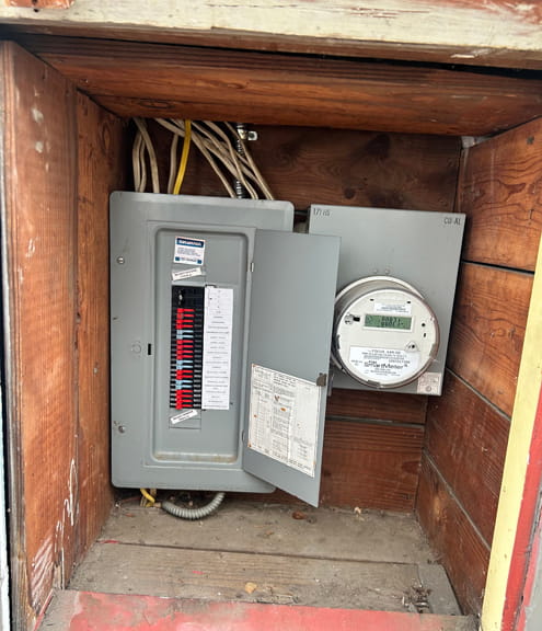 Electrical panel and meter in a shared enclosure close to gas service