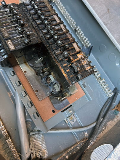 Scorched bus bars inside an old electrical panel, showing the fire risk insurance companies cite